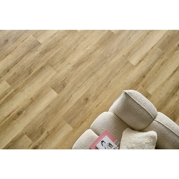 Vinylboden SPC Silent - Tucson Eiche, Landhausdiele, 1.220 x 229 x 5,3 mm - Nahaufnahme eines hellen Holzlaminatbodens mit einer weichen Ottomane und einem Magazin. Der Bodenbelag verleiht dem Raum Wärme.