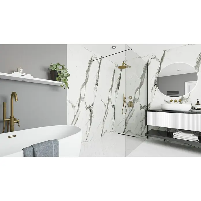 Wetwall Wandpaneel Elite - 16 x 242 cm, Calacatta Statuario, Abgerundete Kante - Elegantes Badezimmer mit freistehender Badewanne, Marmorwand und moderner Dusche. Goldene Armaturen und ein runder Spiegel runden das stilvolle Design ab.