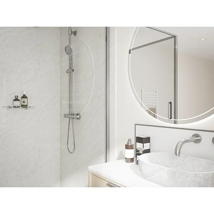Wetwall Wandpaneel Elite - 16 x 242 cm, Carrara Marble, Abgerundete Kante - Ein Badezimmer mit einer Dusche mit Duschkopf, einem runden Spiegel mit Beleuchtung und einem Waschbecken mit Armatur.