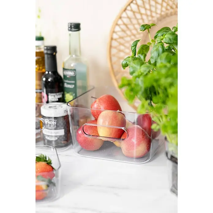 SmartStore Vorratsdose Compact - L x B x H: 20 x 20 x 12 cm, Kunststoff, Transparent - Aufbewahrungsbox aus Kunststoff mit frischen Äpfeln darin, daneben stehen Gewürzflaschen, und ein Basilikumtopf sorgt für einen zusätzlichen Farbtupfer.