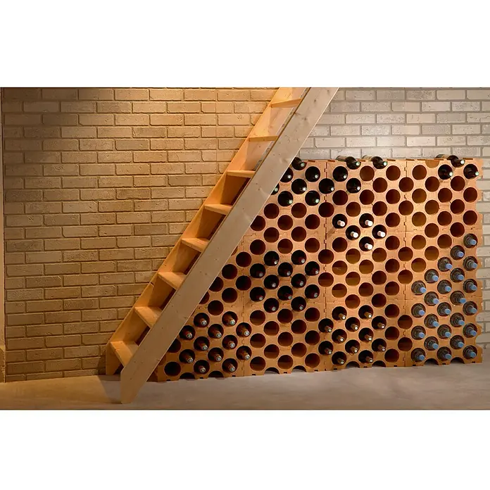 Estantería para botellas Rioja - 26 x 50 x 43 cm - Botellero modular de terracota bajo una escalera de madera. El botellero está lleno de botellas de vino, con una pared de ladrillo claro detrás.