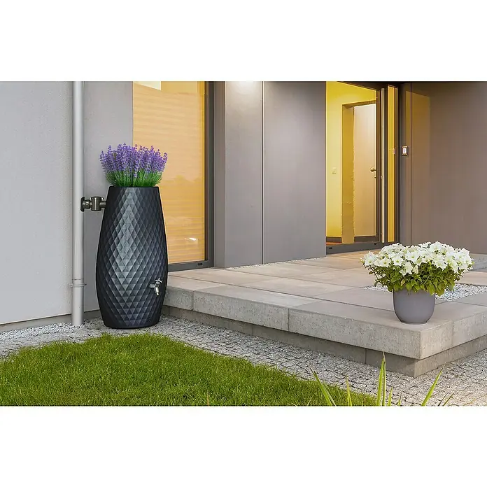 Garantia Regenspeicher Triagon 2 in 1 - 230 l, Graphitgrau, 1 Stk. - Elegante Regentonne in Anthrazit mit geometrischem Muster und Lavendel bepflanzt, neben einem modernen Haus mit Steinterrasse.