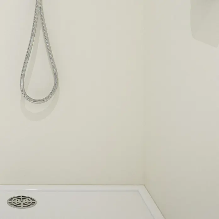 Wetwall Wandpaneel Elite - 16 x 242 cm, Blanco Frost, Abgerundete Kante - Nahaufnahme eines Duschbereichs mit Handbrause und Abfluss in einer hellen, minimalistischen Nasszelle.