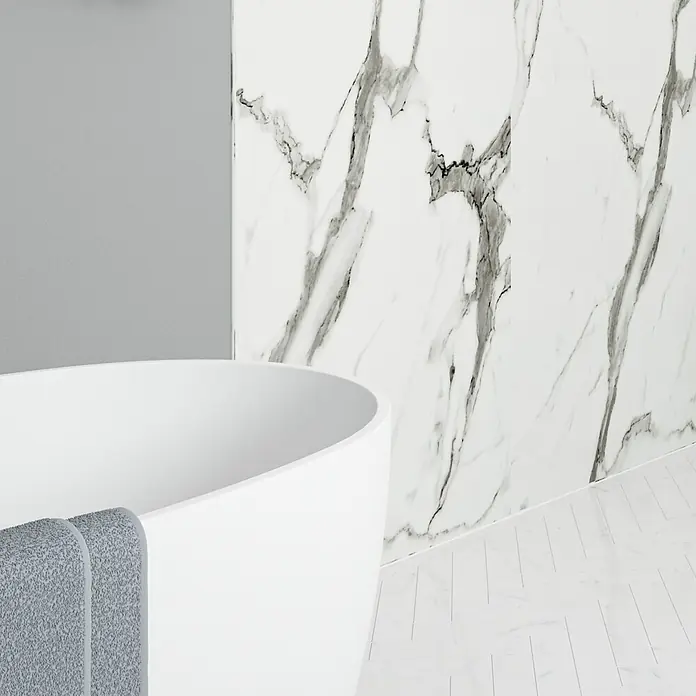 Wetwall Wandpaneel Elite - 16 x 242 cm, Calacatta Statuario, Abgerundete Kante - Elegante Badewanne mit Handtuch und Marmorwand im Hintergrund. Die schlichte Ästhetik und die hochwertige Ausführung laden zum Entspannen ein.
