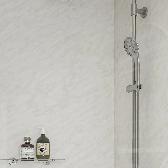 Wetwall Wandpaneel Elite - 120 x 242 cm, Carrara Marble, Nut & Feder System - Duschbereich mit Brausekopf und zwei Flaschen Körperpflegeprodukten auf einem Regal, die für ein entspannendes Duscherlebnis sorgen.