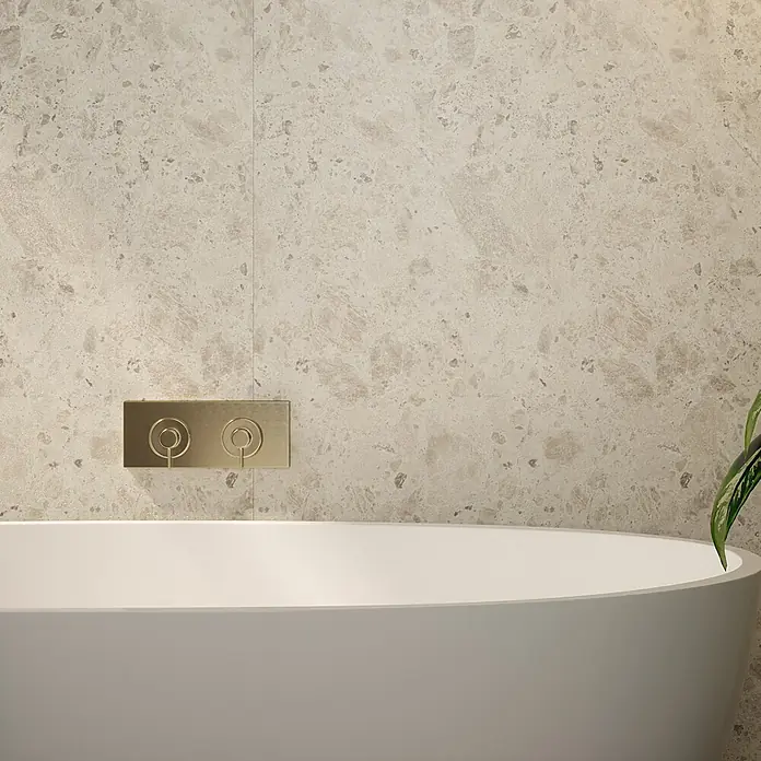 Wetwall Wandpaneel Elite - 16 x 242 cm, Terrazzo Rock, Abgerundete Kante - Nahaufnahme einer modernen, freistehenden Badewanne mit goldener Armatur und beiger Marmorwand für ein luxuriöses Badezimmerambiente.