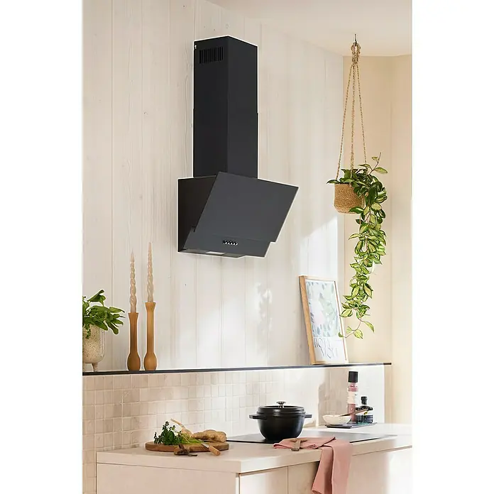 Respekta Schräghaube Sasha - Breite: 60 cm, Mattschwarz - Küchenansicht mit einer modernen, schwarzen Dunstabzugshaube an einer weiß getäfelten Wand, ergänzt durch dekorative Elemente und Küchenutensilien.