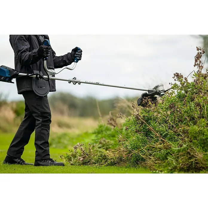 Bosch Professional AMPShare 18V Akku-Freischneider GFR18V-25 BH - 18 V, Schnittbreite Faden: 40 cm, Schnittbreite Messer: 25 cm - Der Bosch Akku-Rasentrimmer im Einsatz, umgeben von grüner Vegetation. Ein unverzichtbares Werkzeug für jeden Gärtner.