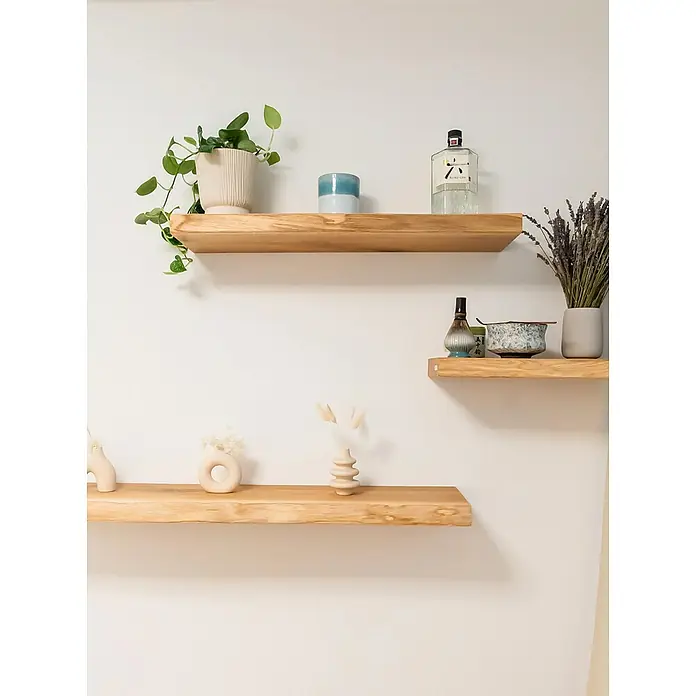holz4home Holzregal -  - Helle Holzregale an einer weißen Wand, dekoriert mit Pflanzen, Kerzen, einer Gin-Flasche und Vasen, die eine warme und gemütliche Atmosphäre schaffen.