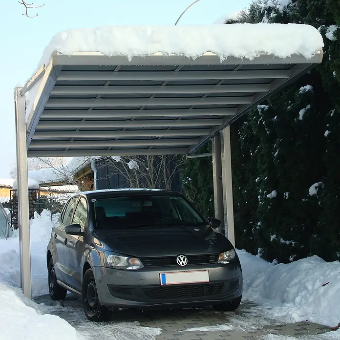 Ximax Carport Miro Next Typ 60 - Außenmaß inkl. Dachüberstand (B x T): 3,03 x 5,79 m, Edelstahl-Look - Grauer VW Polo, der unter einem Carport steht, der mit Schnee bedeckt ist. Der Carport schützt das Auto vor dem Schnee.