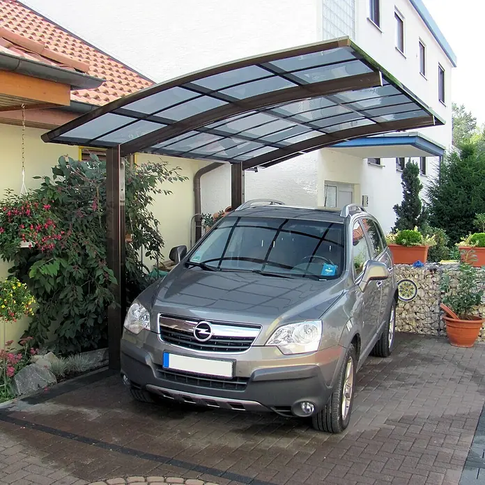 Ximax Carport Portoforte Typ 80 - Außenmaß inkl. Dachüberstand (B x T): 3,01 x 5,56 m, Einzelcarport, Mattbraun - Ein grauer Opel Antara parkt unter einem modernen Carport mit Glasdach, der Schutz vor Witterungseinflüssen bietet und das Fahrzeug aufwertet.