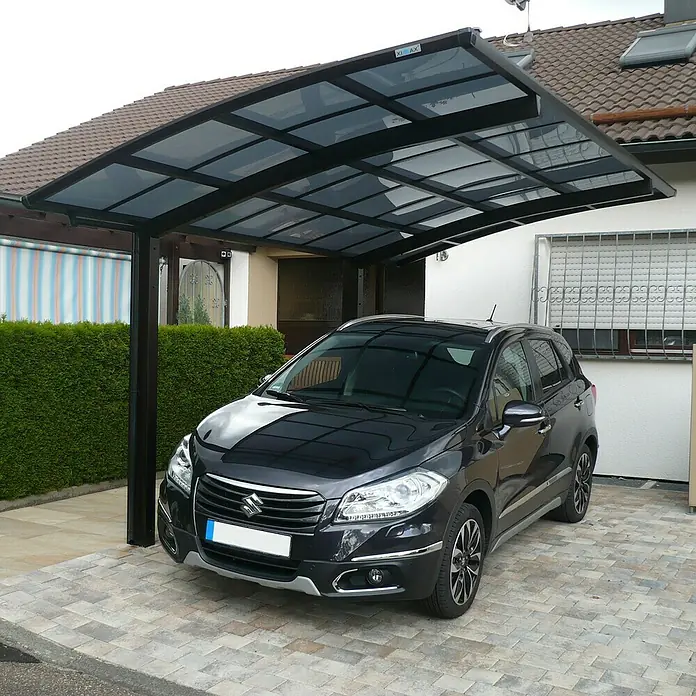 Ximax Carport Portoforte Typ 80 - Außenmaß inkl. Dachüberstand (B x T): 3,01 x 5,56 m, Einzelcarport, Mattbraun - Ein schwarzer Suzuki parkt unter einem modernen Carport mit dunklem Rahmen und transparentem Dach, der Schutz vor Witterungseinflüssen bietet.