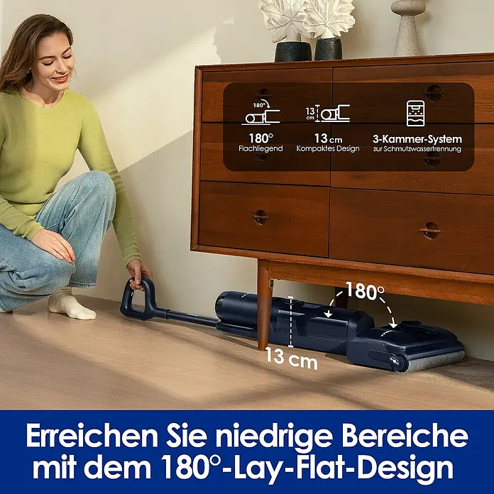 Tineco Akku-Nass-Trockensauger FLOOR ONE S7 Strech - Saugkraft: 21.000 Pa, Akkulaufzeit: 50 min, Wassertankvolumen: 1 l - Eine Frau benutzt einen flachen Staubsauger unter einem Holzschrank. Das Gerät verfügt über ein 180°-Lay-Flat-Design für niedrige Bereiche.