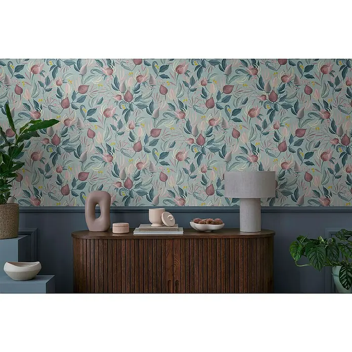 A.S. Création Cosmoliving by Cosmopolitan Vliestapete Blüte - Blau-Rosa-Pink, Floral, 10,05 x 0,53 m - Nahaufnahme einer Kommode mit gerippten Türen, geschmückt mit einer Lampe und Deko-Objekten vor einer floralen Tapete.