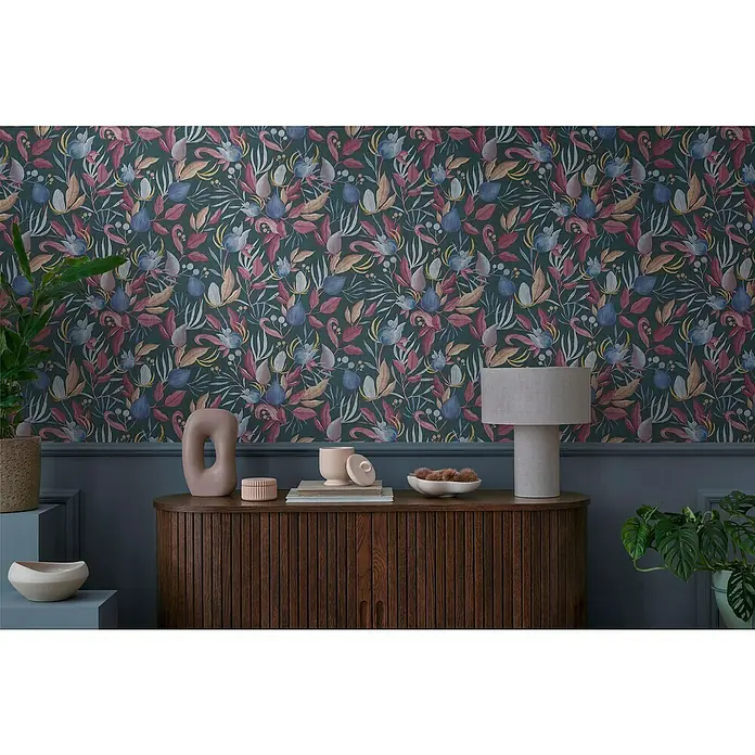 A.S. Création Cosmoliving by Cosmopolitan Vliestapete Blüte - Blau-Grau-Pink, Floral, 10,05 x 0,53 m - Elegante Kommode aus dunklem Holz mit floral gemusterter Tapete im Hintergrund. Die Kommode ist mit stilvollen Deko-Objekten und einer Lampe versehen.