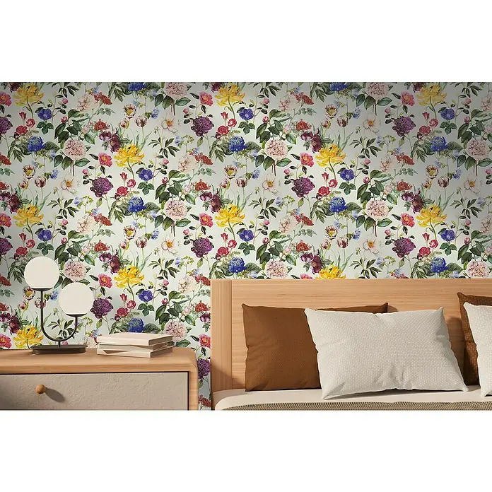 A.S. Création Designdrop Vliestapete Blumen - Bunt, Floral, 10,05 x 0,53 m - Nahaufnahme eines floralen Wandbildes über einem Bett mit Nachttisch, das ein lebendiges und gemütliches Schlafzimmerambiente zeigt.