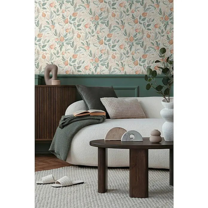 A.S. Création Cosmoliving by Cosmopolitan Vliestapete Blüte - Orange-Creme-Grün, Floral, 10,05 x 0,53 m - Nahaufnahme eines gemütlichen Wohnzimmers mit gemusterter Tapete, einem bequemen Sofa und einem dunklen Holztisch.
