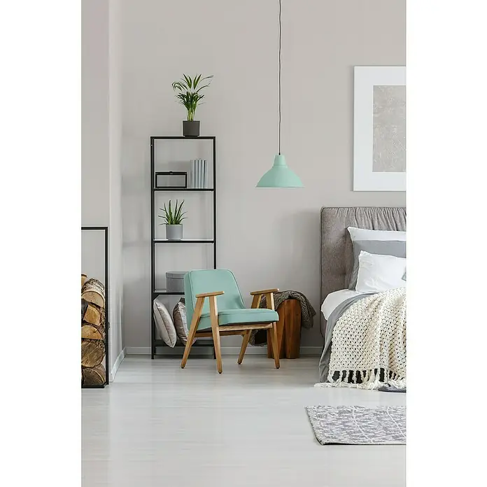 A.S. Création Hygge 3 Vliestapete - Hellcreme, Uni, 10,05 x 0,53 m - Ein helles, modernes Interieur mit einem mintgrünen Sessel im Fokus, ergänzt durch ein Bücherregal, eine Hängelampe und ein stilvolles Bett.