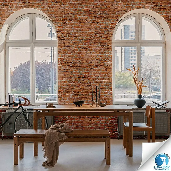 A.S. Création Designdrop Vliestapete Stein - Rot, Steinoptik, 10,05 x 0,53 m - Produktansicht: Einladender Essbereich mit Holztisch, Bank und Stuhl vor einer Backsteinmauer.