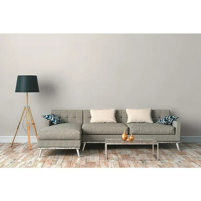 A.S. Création Hygge 3 Vliestapete - Hell-Cremebeige, Uni, 10,05 x 0,53 m - Ein modernes Wohnzimmer mit einem grauen Sofa, Kissen, einem Couchtisch mit Deko und einer Stehlampe.