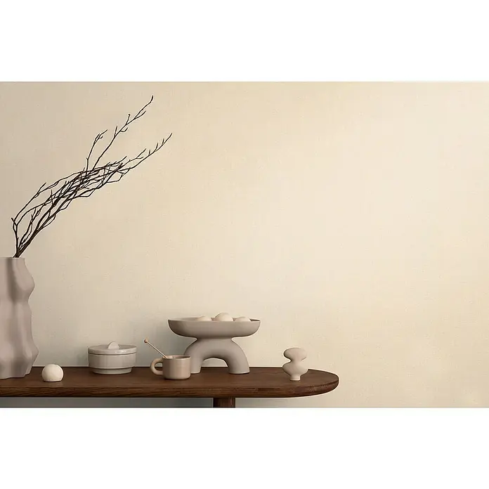 A.S. Création Cosmoliving by Cosmopolitan Vliestapete - Creme-Beige, Uni, 10,05 x 0,53 m - Elegantes Stillleben mit einer Vase mit Zweigen, Keramikschale, Dose, Tasse und dekorativer Figur auf einem dunklen Holztisch vor beigem Hintergrund.