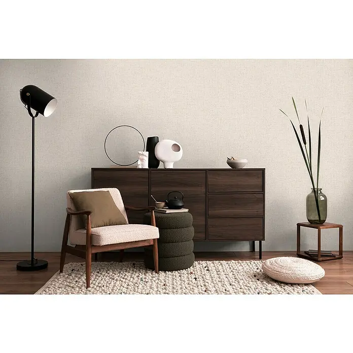 A.S. Création Cosmoliving by Cosmopolitan Vliestapete - Cremegrau, Uni, 10,05 x 0,53 m - Stilvolles Wohnzimmer-Arrangement mit einem modernen Sessel, einer Kommode und dekorativen Elementen für eine gemütliche Atmosphäre.