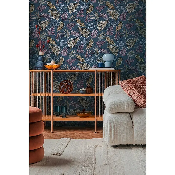 A.S. Création Cosmoliving by Cosmopolitan Vliestapete Ranken - Blau-Lila-Gelb, Floral, 10,05 x 0,53 m - Regal mit Deko vor einer Wand mit tropischem Blättermuster.