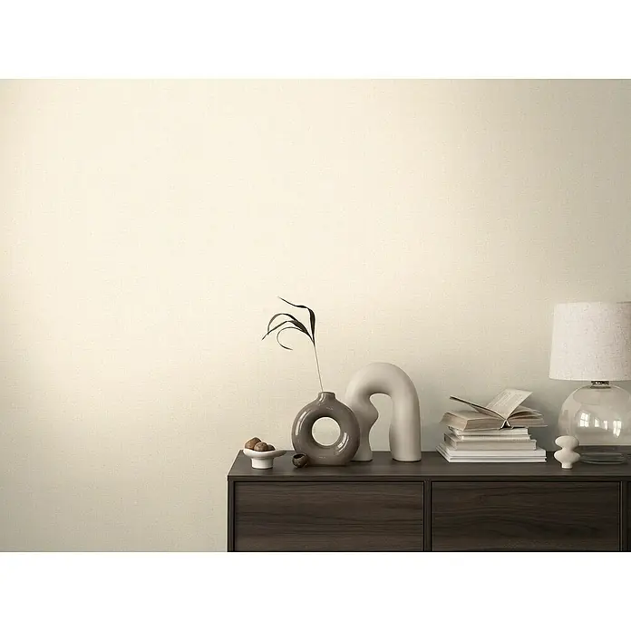 A.S. Création Cosmoliving by Cosmopolitan Vliestapete - Hellcreme, Uni, 10,05 x 0,53 m - Eine Nahaufnahme eines dunklen Holzschranks mit Dekorationen wie einer Lampe, Vasen und Büchern, die eine elegante und ruhige Atmosphäre schaffen.