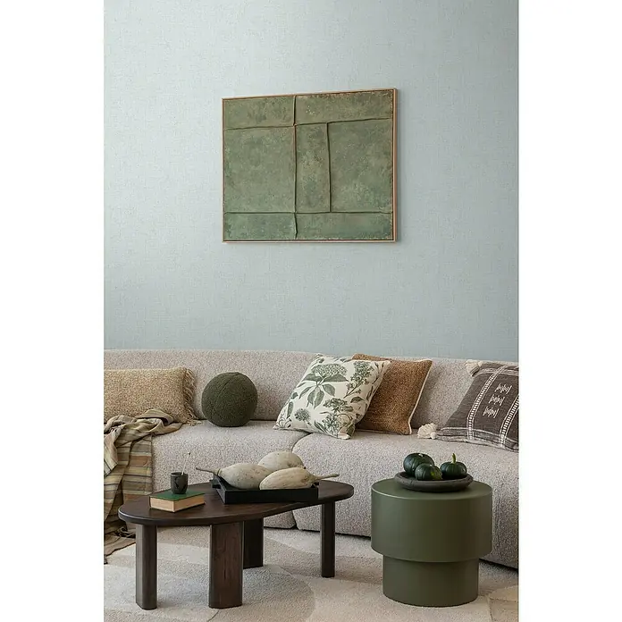 A.S. Création Cosmoliving by Cosmopolitan Vliestapete - Pastellblau, Uni, 10,05 x 0,53 m - Wohnzimmer mit Kunstwerk an der Wand und bequemen Kissen auf einem Bouclé-Sofa, das eine entspannende Atmosphäre schafft.