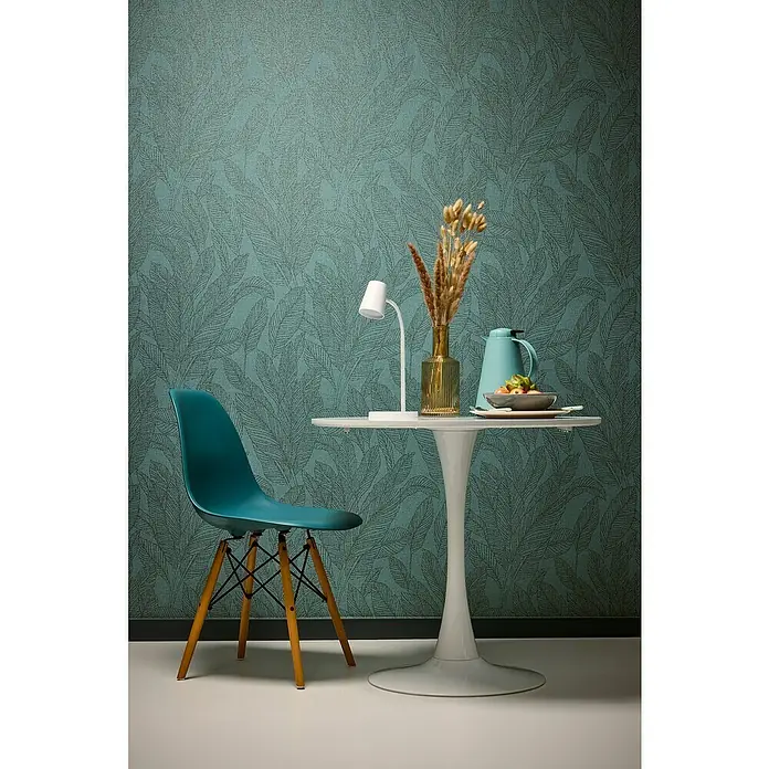 A.S. Création Cosmoliving by Cosmopolitan Vliestapete Blätter - Grün-Blau, Floral, 10,05 x 0,53 m - Einrichten mit Stil: Eine türkisfarbene Eames-Stil Stuhl steht an einem weißen Esstisch, dekoriert mit einer Lampe und einer Vase.