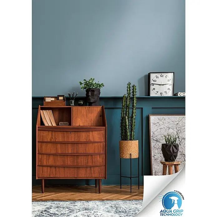 A.S. Création Designdrop Vliestapete - Blau, Uni, 10,05 x 0,53 m - Einrichten mit Stil: Antiker Sekretär aus Holz, grüner Kaktus im Topf und eine elegante Uhr.