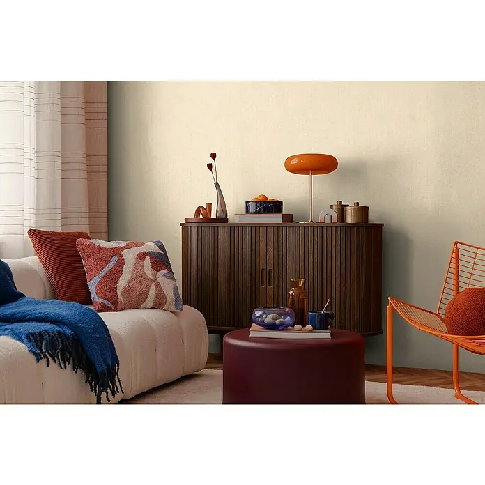 A.S. Création Cosmoliving by Cosmopolitan Vliestapete - Beige II, Uni, 10,05 x 0,53 m - Gemütliches Wohnzimmer mit einem Lowboard aus Holz, einem Sofa und einem orangefarbenen Sessel. Die Einrichtung ist modern und stilvoll.