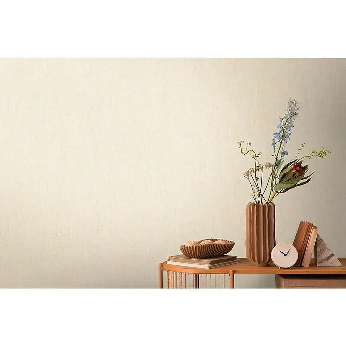A.S. Création Cosmoliving by Cosmopolitan Vliestapete - Beige, Uni, 10,05 x 0,53 m - Stillleben mit Keramikvase, Blumen und Büchern auf einem Holzregal vor einer beigen Wand.