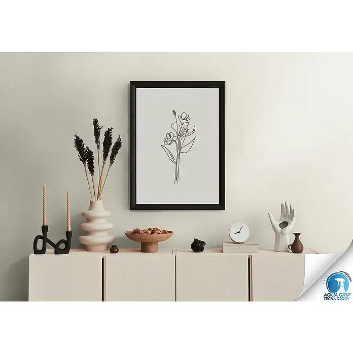 A.S. Création Designdrop Vliestapete - Creme, Uni, 10,05 x 0,53 m - Elegantes Interieur mit einem gerahmten Blumendruck, stilvollen Vasen, Kerzen und einer dekorativen Handskulptur auf einer Kommode.