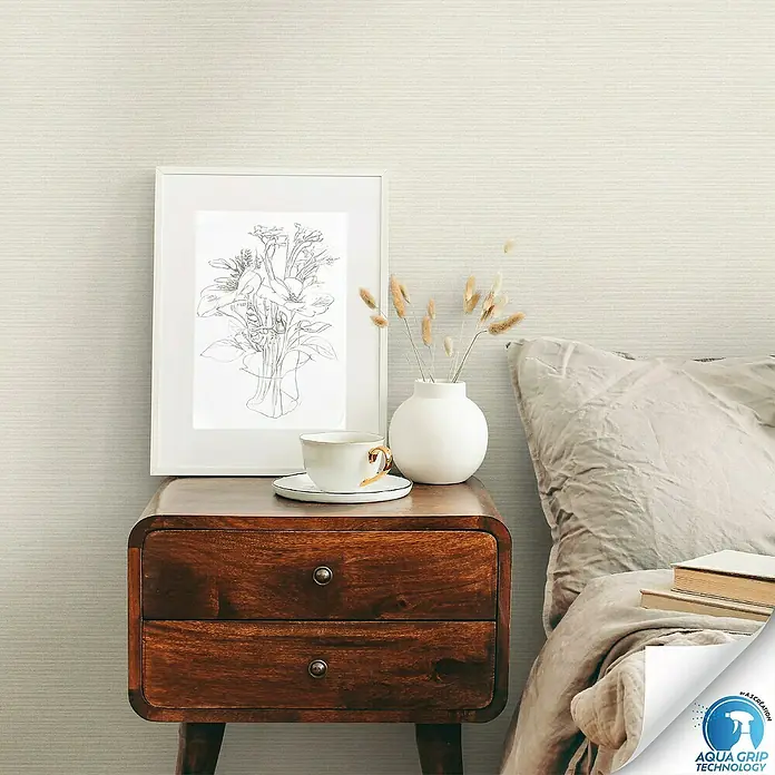 A.S. Création Designdrop Vliestapete - Beige, Uni, 10,05 x 0,53 m - Nahaufnahme eines stilvollen Nachttisches mit Dekorationen, der die elegante Holzstruktur und die raffinierte Gestaltung hervorhebt.
