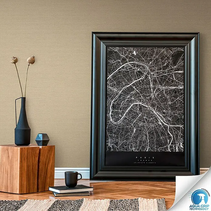 A.S. Création Designdrop Vliestapete - Braun, Uni, 10,05 x 0,53 m - Detailaufnahme eines Wandbildes mit einer schwarzen Stadtkarte von Paris, das an einer beigen Wand lehnt.