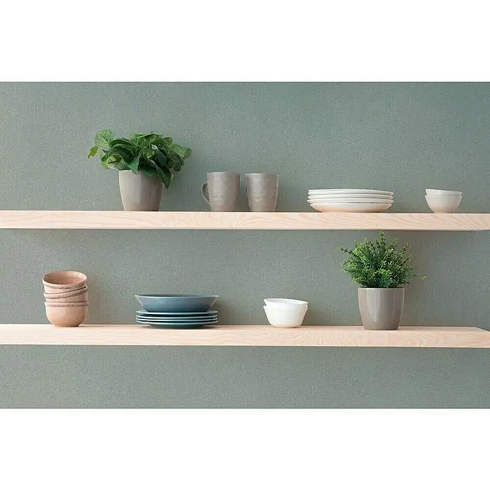 A.S. Création Hygge 3 Vliestapete - Pastellgrün, Uni, 10,05 x 0,53 m - Schlichte Holzregale an einer grünen Wand, dekoriert mit Geschirr, Tassen und Pflanzen. Eine minimalistische und stilvolle Wandgestaltung im Interieur.