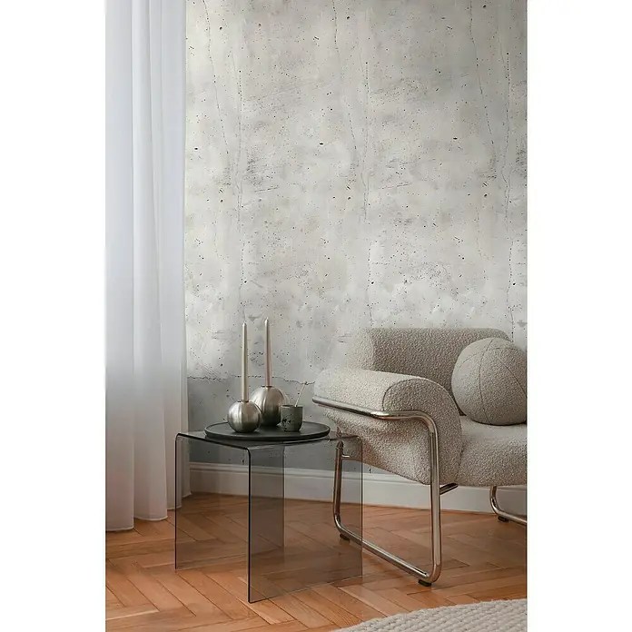 A.S. Création Cosmoliving by Cosmopolitan Fototapete Beton - B x H: 159 x 280 cm, Vlies - Eine Nahaufnahme eines minimalistischen Interieurs mit einem eleganten Sessel und einem modernen Glastisch, der Kerzenständer trägt.