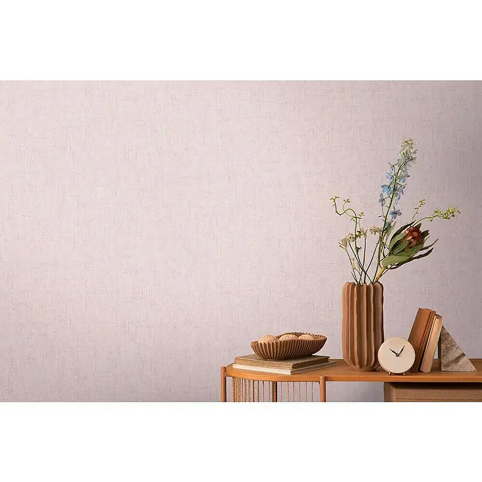 A.S. Création Cosmoliving by Cosmopolitan Vliestapete - Altrosa, Uni, 10,05 x 0,53 m - Nahaufnahme eines Zimmers mit einer Vase, Büchern und einer Schale auf einem Holzregal mit einer hellrosa Wand im Hintergrund.