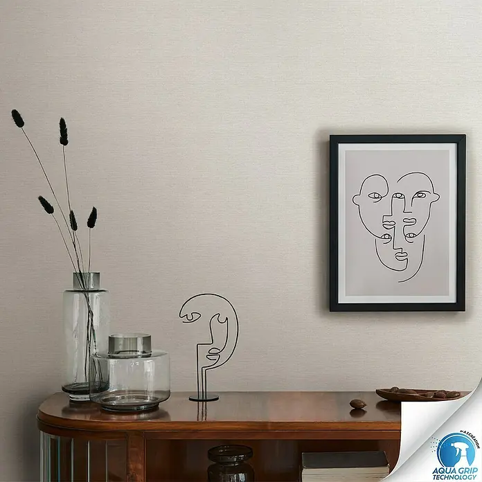 A.S. Création Designdrop Vliestapete - Cremegrau, Uni, 10,05 x 0,53 m - Nahaufnahme eines Dekors mit einer Vase, Skulptur und einem gerahmten Kunstdruck auf einem Sideboard.