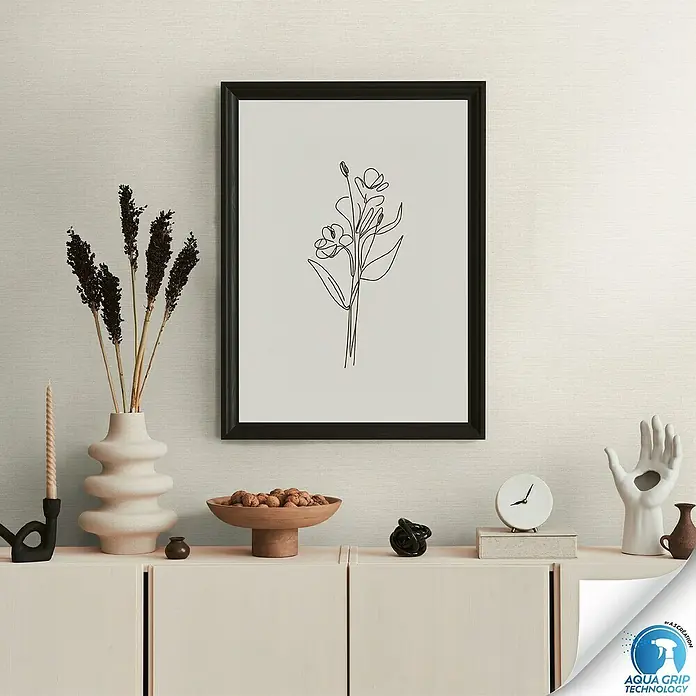 A.S. Création Designdrop Vliestapete - Creme, Uni, 10,05 x 0,53 m - Dekoratives Stillleben mit Blumenbild im Rahmen über einer Kommode, stilvolle Raumgestaltung.