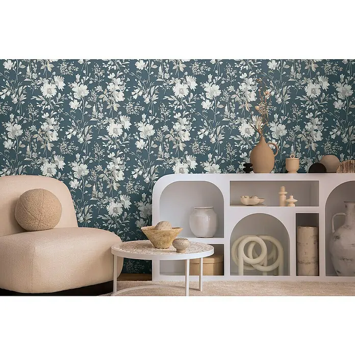 A.S. Création Cosmoliving by Cosmopolitan Vliestapete Blüten - Blau-Metallic-Weiß, Floral, 10,05 x 0,53 m - Elegantes Wohnzimmer mit blauer Blumentapete, beigefarbenem Sessel und weißem Regal. Dekorative Vasen und Schalen vervollständigen das stilvolle Ambiente.