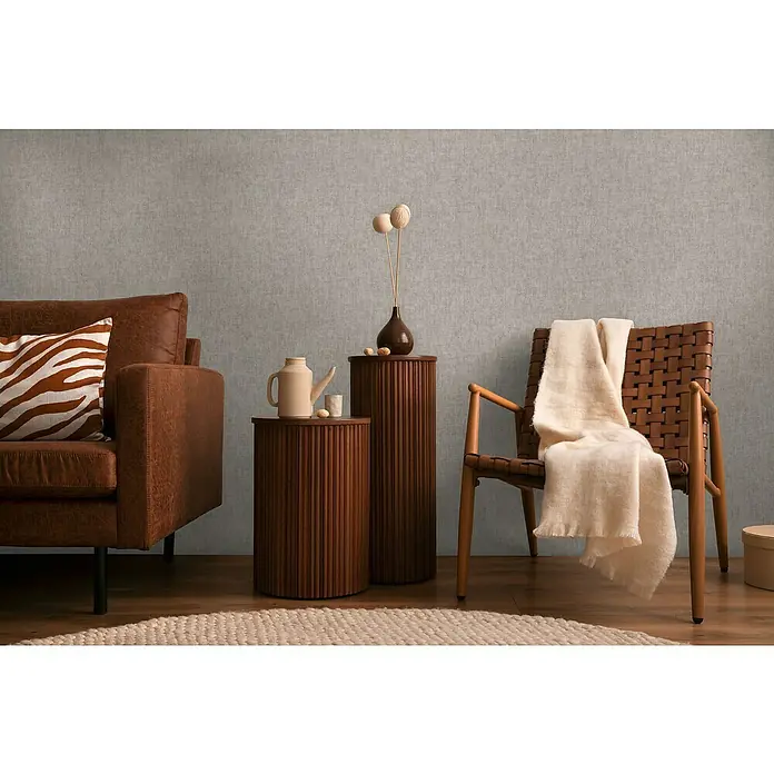 A.S. Création Cosmoliving by Cosmopolitan Vliestapete - Grau, Uni, 10,05 x 0,53 m - Einrichten mit Stil: Braunes Ledersofa, Beistelltische aus Holz und ein Webstuhl-Stuhl mit Decke schaffen ein gemütliches Ambiente.