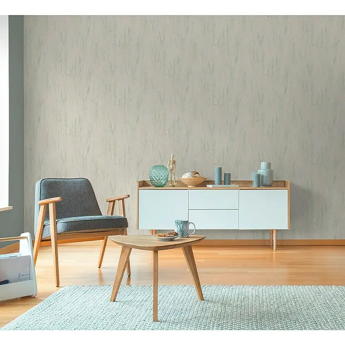 A.S. Création Hygge 3 Vliestapete Floral - Creme-Blau-Grün, Floral, 10,05 x 0,53 m - Elegantes Wohnzimmer mit gemusterten Tapeten, einem stilvollen Sessel und einem Sideboard mit dekorativen Akzenten für ein gemütliches Ambiente.