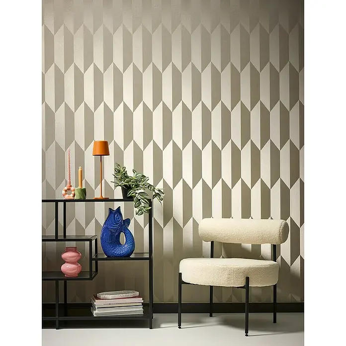 A.S. Création Cosmoliving by Cosmopolitan Vliestapete 3D-Grafik - Silber-Metallic-Braun, Grafisch, 10,05 x 0,53 m - Einrichtungsidee mit modernem Regal, dekoriert mit farbenfrohen Vasen, einer Pflanze und einer auffälligen blauen Fischfigur, neben einem stilvollen Sessel.