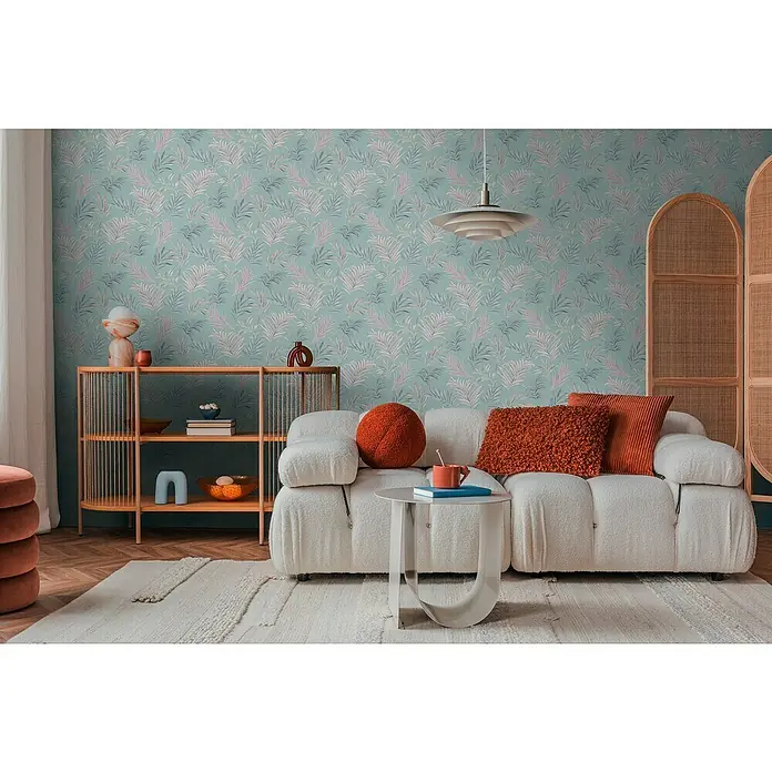 A.S. Création Cosmoliving by Cosmopolitan Vliestapete Ranken - Blau-Rosa-Grau, Floral, 10,05 x 0,53 m - Gemütliches Wohnzimmer mit einem cremefarbenen Modulsofa, Akzentkissen in Orange und einem gemusterten Hintergrund.