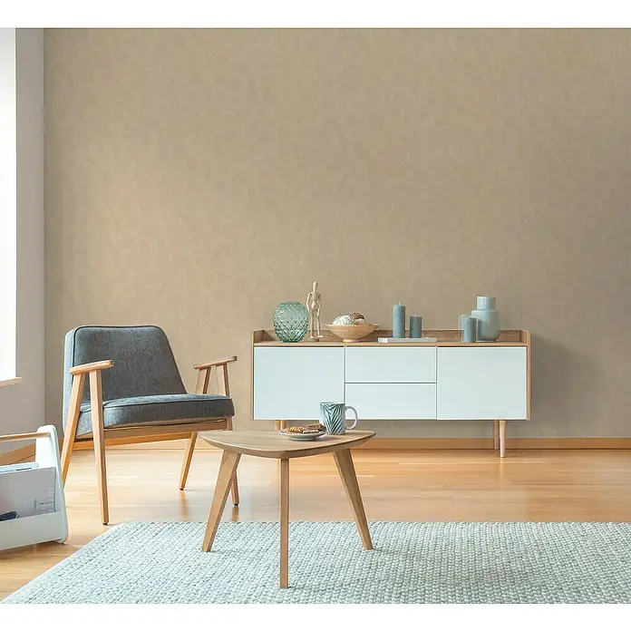 A.S. Création Hygge 3 Vliestapete Kreise - Beige-Orange, Grafisch, 10,05 x 0,53 m - Wohnzimmer mit einem grauen Sessel, einem weißen Sideboard und einem dreieckigen Holztisch auf einem hellen Teppich.