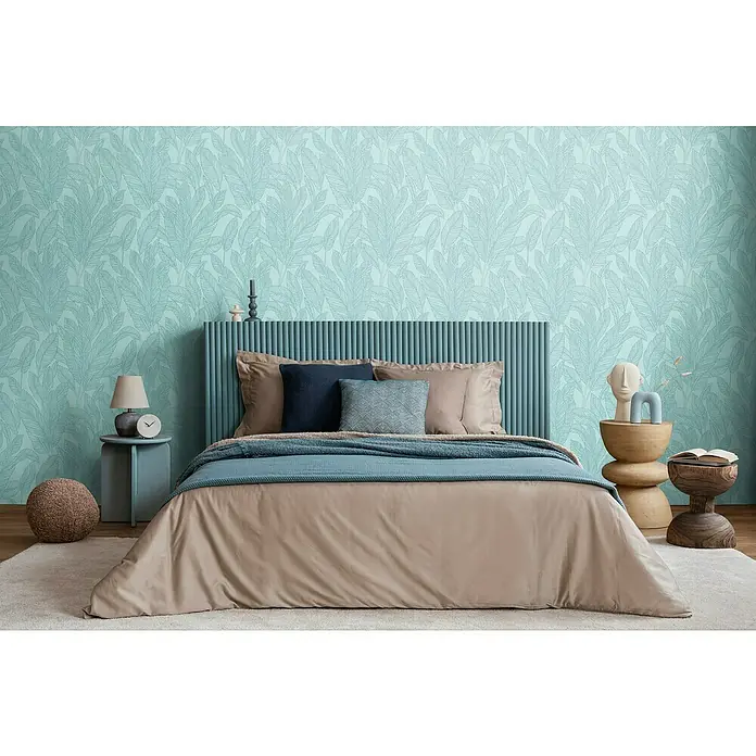 A.S. Création Cosmoliving by Cosmopolitan Vliestapete Blätter - Blau-Gold, Floral, 10,05 x 0,53 m - Schlafzimmer mit großem Bett, blauem Kopfteil und Dekokissen vor einer gemusterten Tapete.