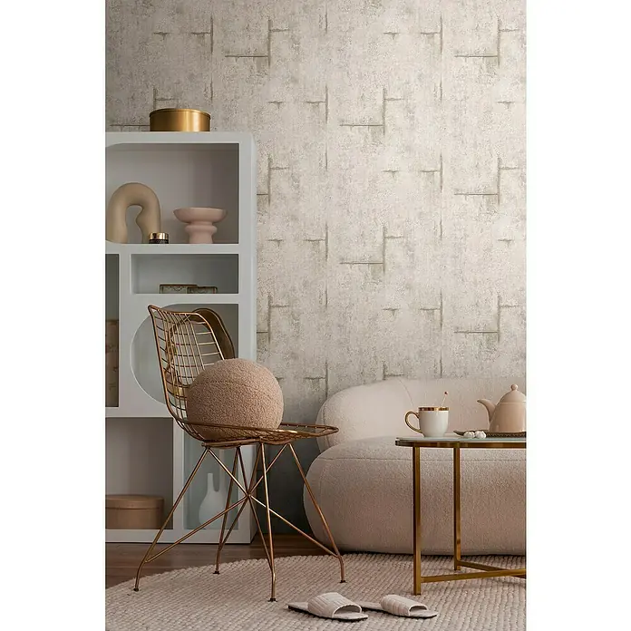 A.S. Création Cosmoliving by Cosmopolitan Vliestapete Beton - Grau-Braun-Weiß, Betonoptik, 10,05 x 0,53 m - Nahaufnahme eines Wohnraums mit strukturierten Tapeten, einem weißen Regal und goldenen Akzenten auf Möbeln und Deko.