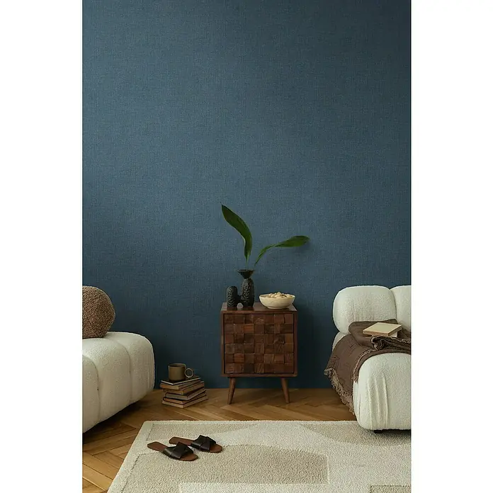 A.S. Création Cosmoliving by Cosmopolitan Vliestapete - Blau meliert, Uni, 10,05 x 0,53 m - Ein stilvolles Interieur mit einem Nachttisch aus Holz, einer Vase mit grünen Blättern und bequemen Sitzmöbeln in einem gemütlichen Raum.